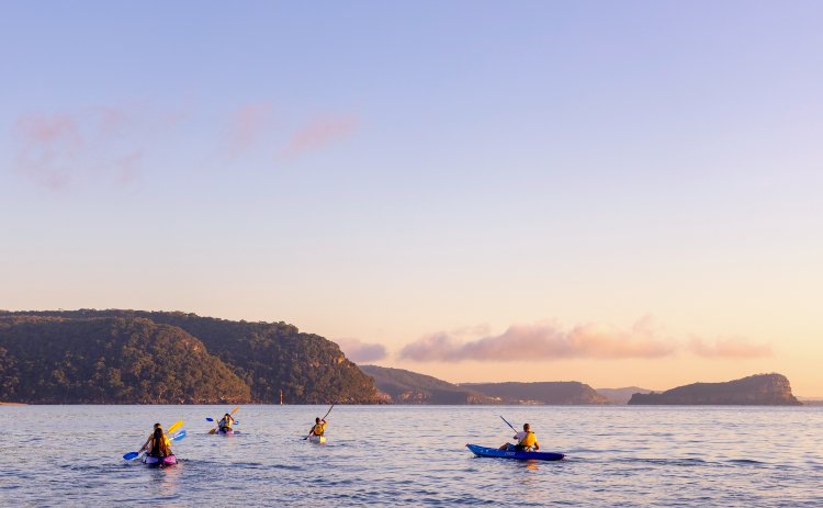 Friends enjoying a sunrise kayaking experience in Pittwater with Pittwater Kayak Tours, Palm Beach.