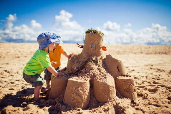 Two little boys building large sandcastle on the beach