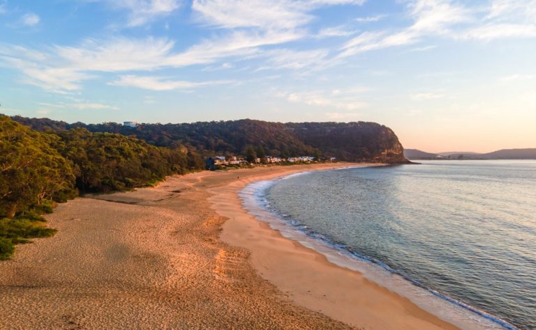 Calm seas aerial sunrise at Pearl Beach on the Central Coast, NSW, Australia.