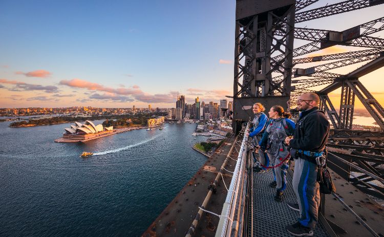 Friends enjoying a twilight BridgeClimb Sydney experience overlooking Sydney Harbour.
