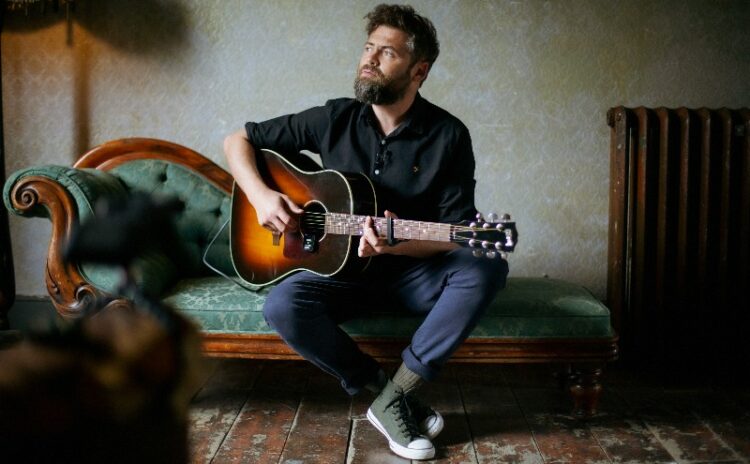 Passenger - man with a guitar on a green sofa