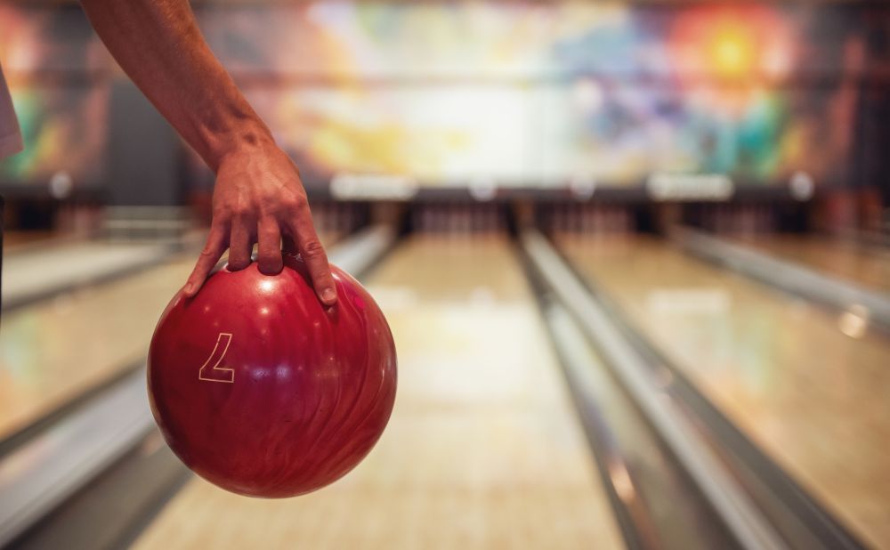 Man's hand holding a red bowling ball ready to throw it