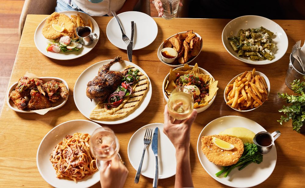 spread of food for a group meal, featuring chicken, pasta, nachos and more.