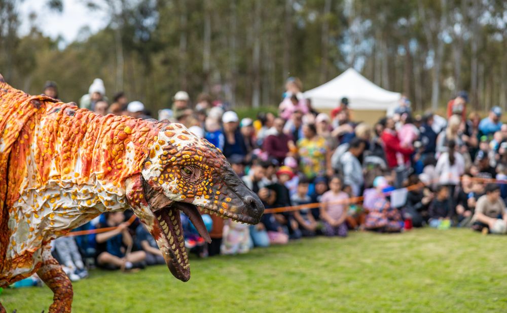 life size Dinosaur puppet with a crowd looking on