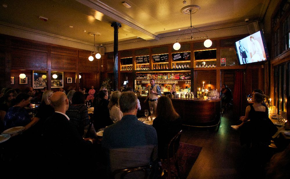People sitting in a pub listening to a speaker sharing Sydney crime stories 