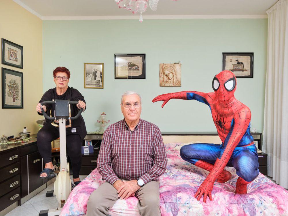 Manuel (28) poses with his grandparents in their bedroom in Livorno, Tuscany, Italy. Manuel works as a butcher and has been practicing cosplay since 2018; in the photo he plays Spider-Man, a Marvel Comics character.