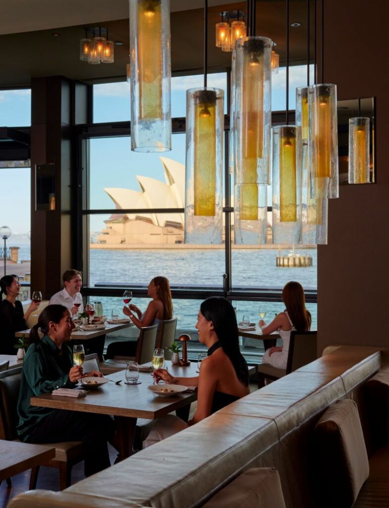 Customers drinking champagne by windows that overlook the Opera House 