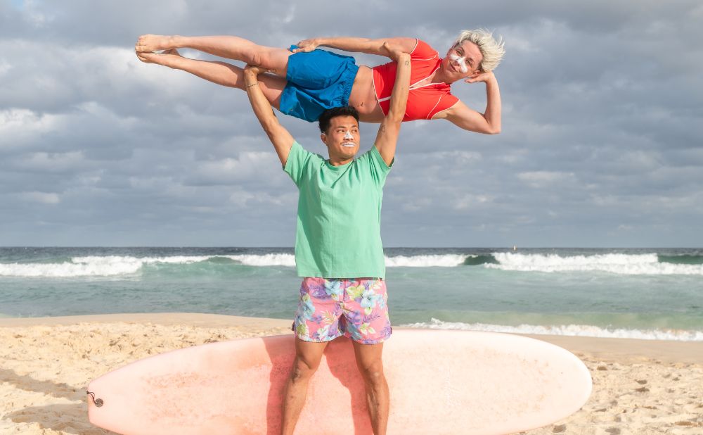 2 people on the beach one is holding the other above his head. Its a still to promote the show Waverider