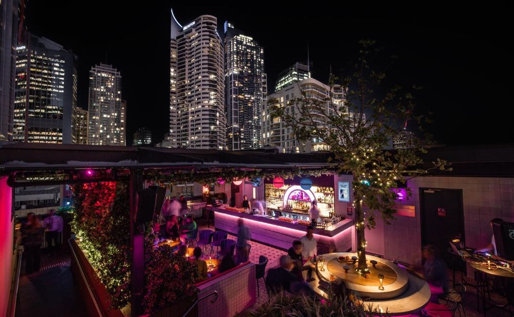 Above 319 rooftop bar at night with pink lighting, city skyline views, and Darling Harbour buildings in background