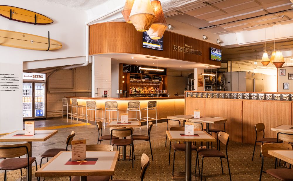 Interior of Freshie Clubhouse Brookvale with timber bar, surfboards on the wall and sport on the screens