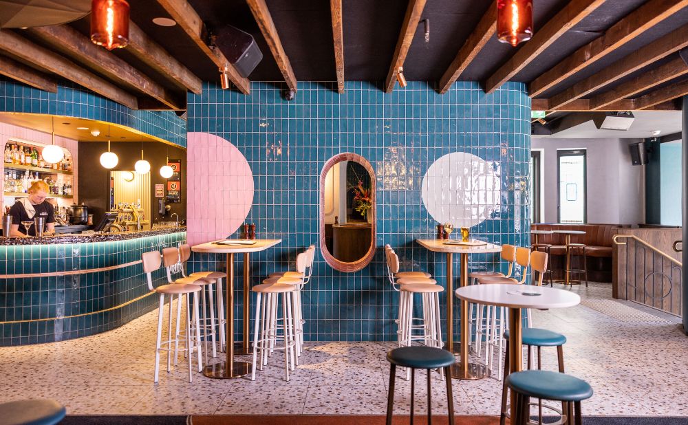 Bar and high tables at Penny's Hotel Potts Point with teal tiled walls and pink circle detail