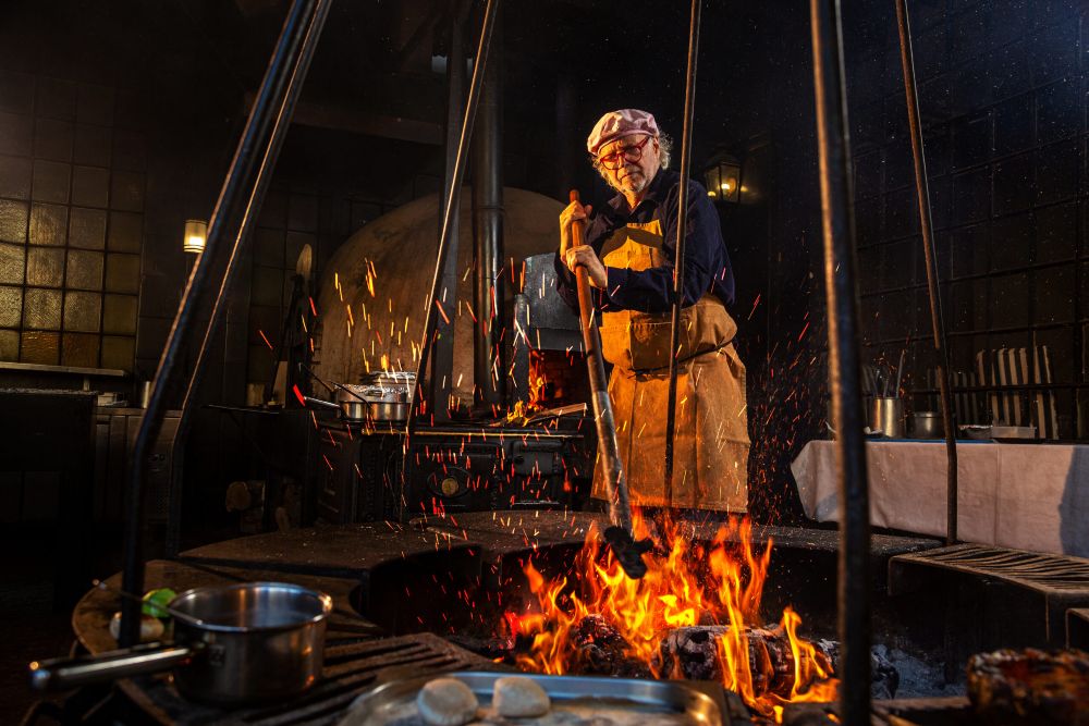 Man tending a fire cooking pit