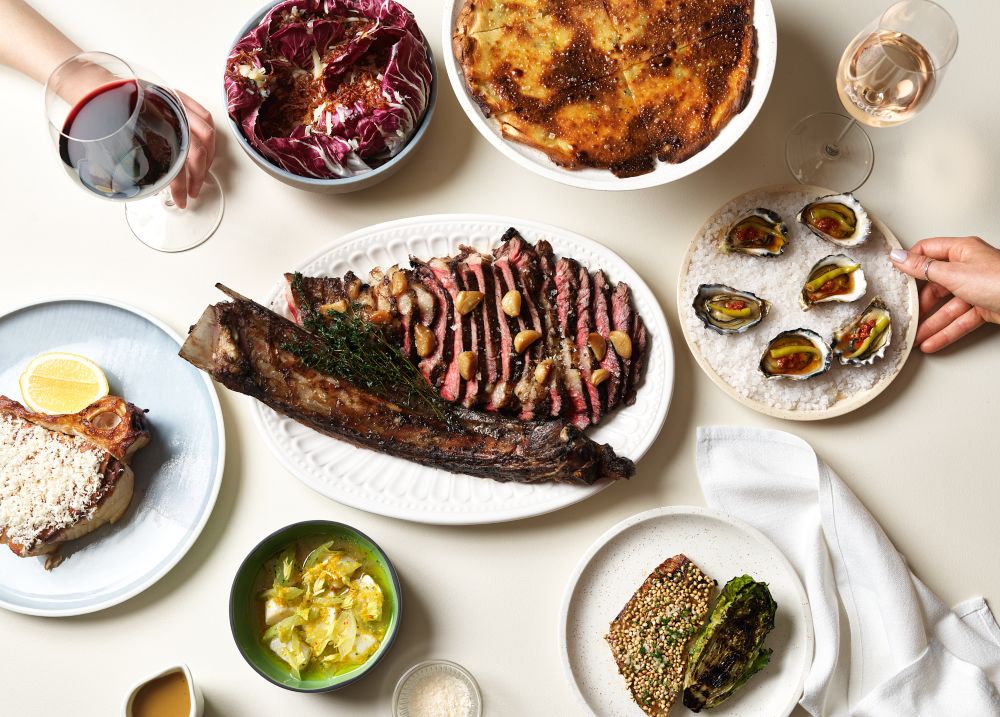Beef centred on a table of food with oysters and side dishes
