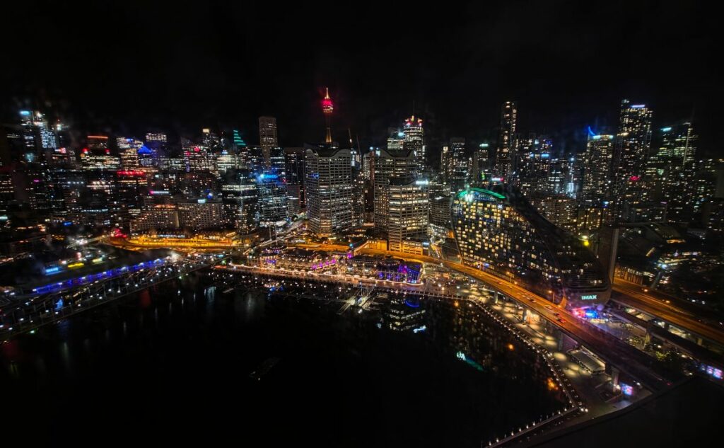 Sydney Darling Harbour and CBD skyline illuminated at night, showing Sydney Tower and city buildings reflected in the water